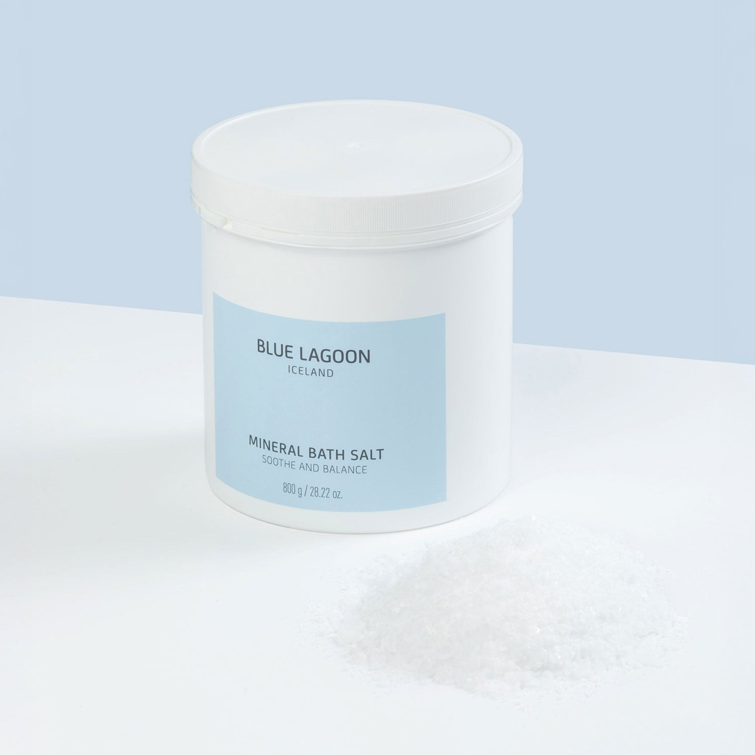 Mineral Bath Salt in white plastic jar on light blue surface