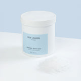 Mineral Bath Salt in white plastic jar on light blue surface